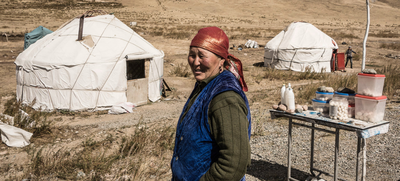 Kirgisische Bäuerin verkauft ihre Waren vor der eigenen Hütte