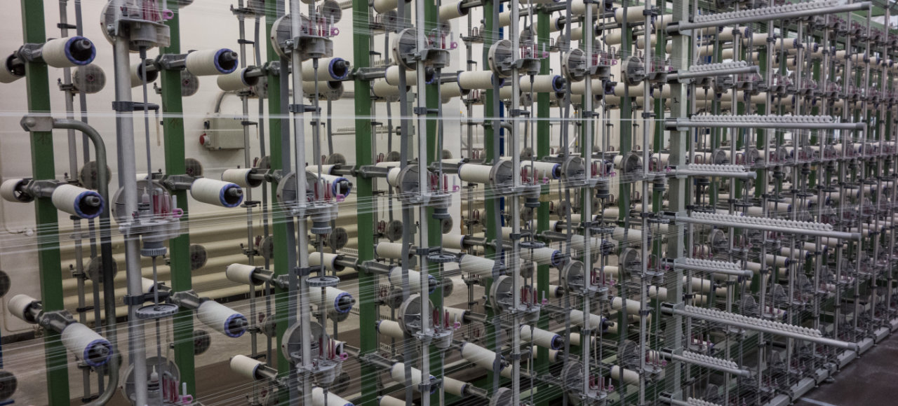 Hunderte Garnspulen auf Zettelgatter für das Weben von Bio Textilien